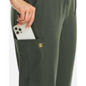 A pair of women's full waist joggers in olive green with a side pocket holding a smartphone. Features a small logo.