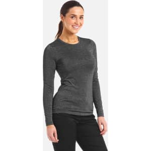 A woman wears a long-sleeved, grey underscrub tee. The top has a fitted style and includes a logo.