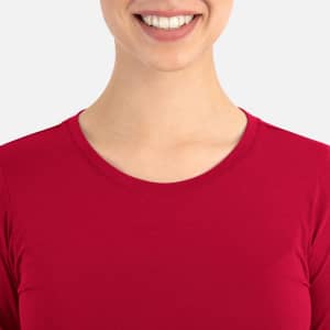 A close-up view of a red women's underscrub tee featuring a round neckline. The model is smiling.