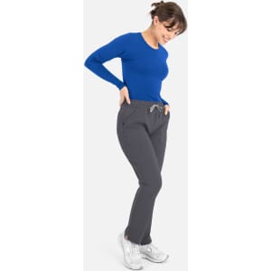 A woman is wearing a blue long-sleeve underscrub tee paired with grey pants and white shoes.