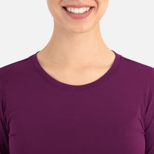 A women's underscrub tee in a rich plum colour with a round neckline. The model smiles while wearing it.