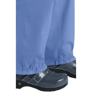 Light blue Lindsey Pants paired with shiny black footwear, featuring a logo. The fabric has a relaxed fit.