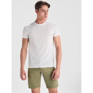 A white T-shirt worn by a young man, paired with khaki shorts, featuring a simple design and a logo.