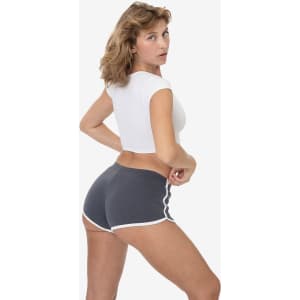 A model wearing grey interlock running shorts with white trim, paired with a white crop top, facing away from the camera.