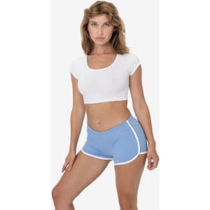 Interlock running shorts in light blue with white trim, paired with a white crop top. The model is standing confidently.