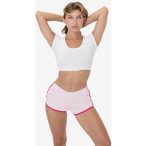 Light pink sports shorts with a contrasting pink trim, modelled by a woman in a white top. The shorts have a logo.