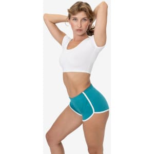 A model poses in turquoise interlock running shorts with white trim and a fitted white top. The design includes a logo.