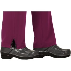 A pair of purple pants with a split hem, worn with black clogs. The pants have a logo on the waistband.