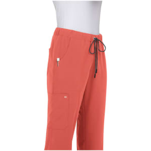 Coral-coloured pants with an elastic waistband and pockets, featuring a drawstring and a logo on the side.