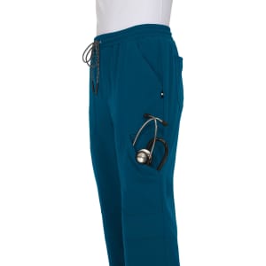 A pair of teal jogger pants featuring a pocket for a stethoscope and an adjustable waistband. It has a logo on the side.