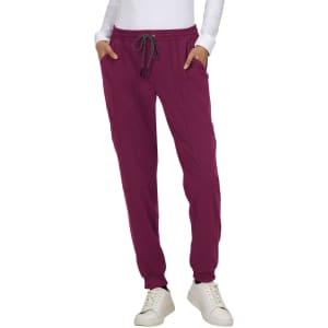 A person wearing burgundy jogger pants with a drawstring waist, paired with a white long-sleeve top and white sneakers.