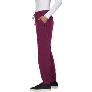 A pair of burgundy jogger pants with pockets and a drawstring waist, styled with a white long-sleeve top and black shoes.