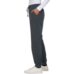 A pair of dark grey jogger pants with a drawstring waist and side pockets, styled with a white long-sleeve top and white shoes.