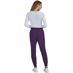 A pair of purple jogger pants worn by a model. The model is facing away, wearing a white top and white shoes.