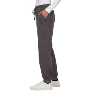 A pair of dark grey jogger pants with an elastic waistband and side pocket, worn with a white long-sleeve top and white shoes.