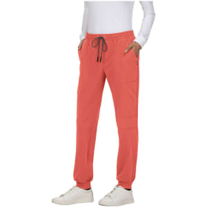 A person stands in coral jogger pants featuring pockets and a drawstring, paired with white shoes.