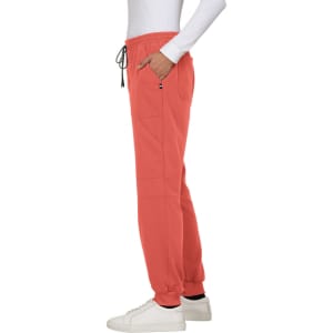 A pair of coral jogger pants with side pockets, featuring an elastic waistband and a drawstring, styled with a white top.
