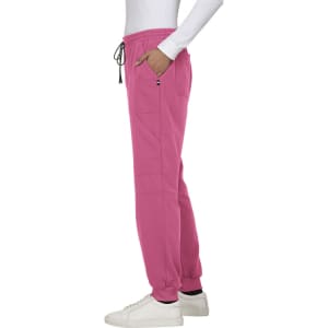 A pair of pink jogger pants with a drawstring waist and pockets, worn with a white long-sleeve top and shoes.