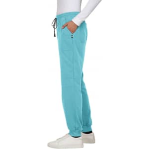 A side view of teal jogger pants with pockets, paired with a white top and white sneakers, featuring a logo.