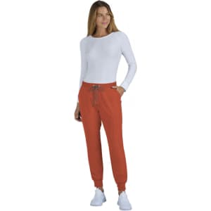 A woman wearing orange jogger pants and a long-sleeve white top, featuring a brand logo.