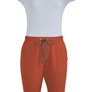 A pair of rust-coloured jogger pants with an elastic waistband and drawstring, featuring pockets and a logo.