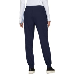 A pair of navy jogger pants with an elastic waistband and pockets, viewed from the back. The model is wearing a white long-sleeve top.