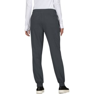 A person wearing dark grey jogger pants, with an elastic waistband and cuffed ankles, standing with their back facing the camera.
