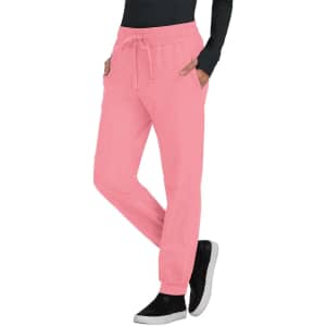A pair of pink jogger pants with pockets and a drawstring waist, styled with a black top and shoes.