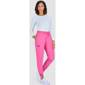 A woman wearing bright pink jogger pants and a light blue long-sleeve top, standing against a grey background.
