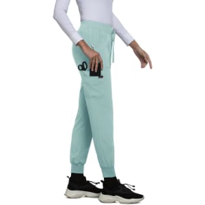 A pair of mint green joggers with pockets, featuring a logo, styled with a fitted top and sneakers.