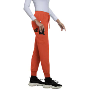 An orange jogger featuring a zip pocket, worn by a person in a fitted white top and black sneakers.