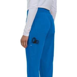 Blue scrubs with a pocket visible, holding a pair of black scissors. The model is facing away from the camera.