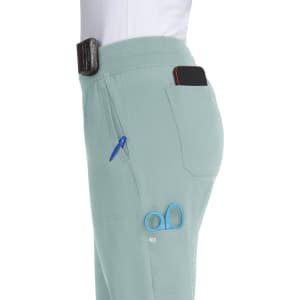 A pair of light green jogger pants with multiple pockets, holding a phone, a pen, and scissors. Features a logo.