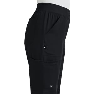 A side view of black boot cut pants featuring pockets and an elastic waistband, with a logo on the leg.