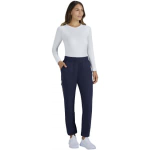A woman is wearing limited edition navy Harper pants paired with a white long-sleeve top and white shoes.