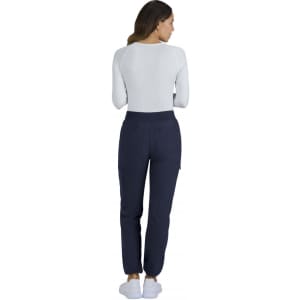 A woman is wearing navy Harper pants and a white long-sleeve top, viewed from the back. The pants have a logo.