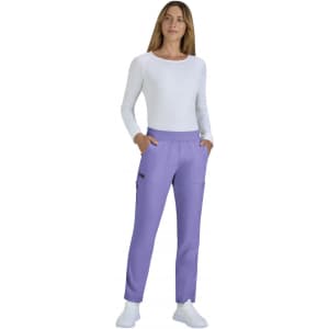 A woman is wearing limited edition purple Harper pants with pockets, paired with a white long-sleeve top and white shoes.