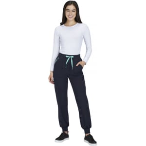 A woman in a white long-sleeve top and navy joggers with a mint green drawstring and pockets. The joggers have branding.