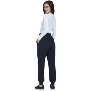 A woman wearing navy jogger pants with pockets, facing away, paired with a long-sleeve white top.