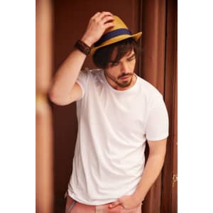 A white t-shirt worn by a man, complemented by a straw hat, with a neutral background.