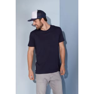 A navy blue T-shirt worn by a smiling man, paired with a two-tone cap, against a light blue background.