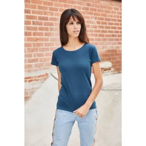 A model wearing a navy blue basic T-shirt paired with light blue jeans, standing against a brick wall.