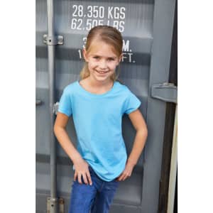 A girl wearing a light blue T-shirt and jeans, posing in front of a container. The shirt has a logo.