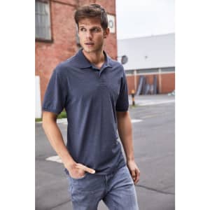 A man wearing a dark grey polo shirt and light jeans, standing outdoors with a casual pose.