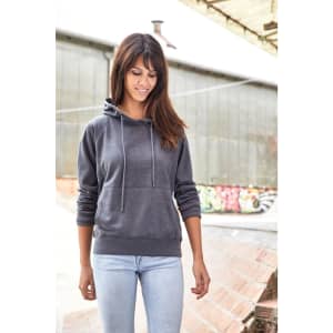 A grey ladies hoodie with a pouch pocket and drawstrings, worn with light blue jeans against an industrial background.