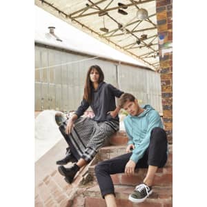 A hooded jumper in teal and a hooded jumper in dark grey are worn by two models sitting on steps.