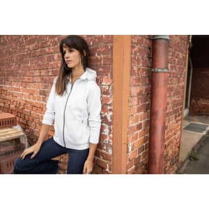 A zip hoodie in light grey displayed on a model against a brick wall, featuring a hood and zip closure.