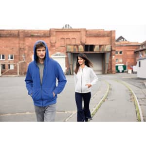 A blue men's zip hoodie and a white women's zip hoodie are worn by models in an urban setting.