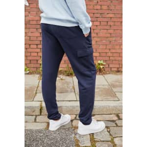 Navy men's lounge pants featuring side pockets, shown from the back against a brick wall background.