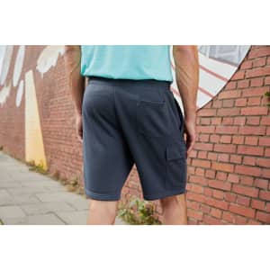 Men's lounge shorts in grey with a pocket, displayed from the back against a brick wall background.